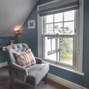 Vertical Sliding Windows in a bedroom with a grey chair to look out the window